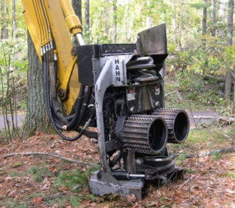 The fixed-head harvester head is mounted to a boom and shows two feeding rolls and four delimbing knives.