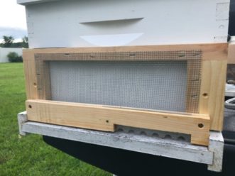 An anti-robbing screen mounted to the front of a langstroth bee hive.