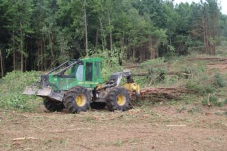 A picture of a grapple skidder pulling a bunch of trees along a skid trail.